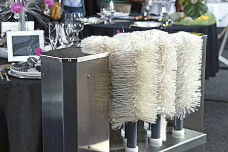 Ein Bild mit der Poliermaschiene PM2. Eine Maschiene aus Edelstahl zum Polieren von Gläsern. Die Gläser werden beim Polieren von 8 Polierelementen umfasst, getrocknet sowie Poliert.